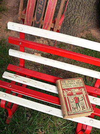 An old book, an old bench, and an old sled await buyers at a country flea market.